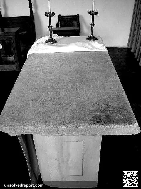 Medieval altar stone (stone mensa). Dug up in the churchyard; it has the usual five consecration crosses, one carved ne…